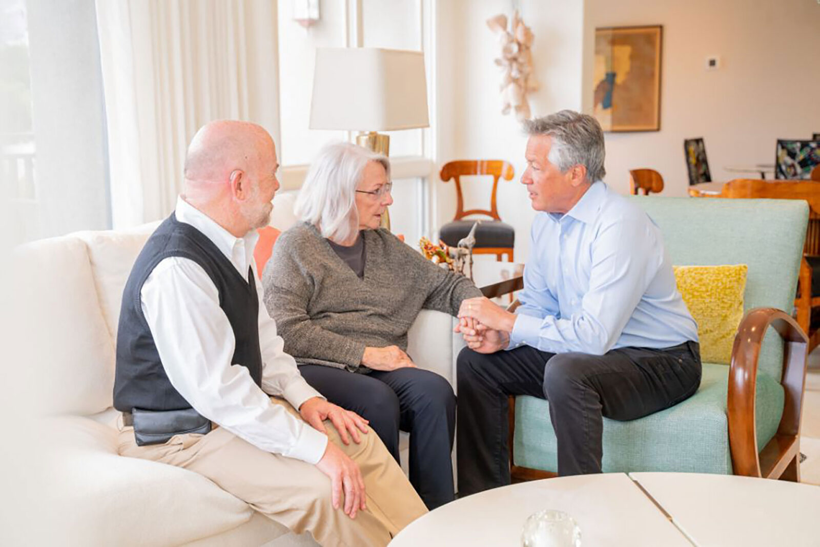 Three people engaged in a serious conversation indoors.