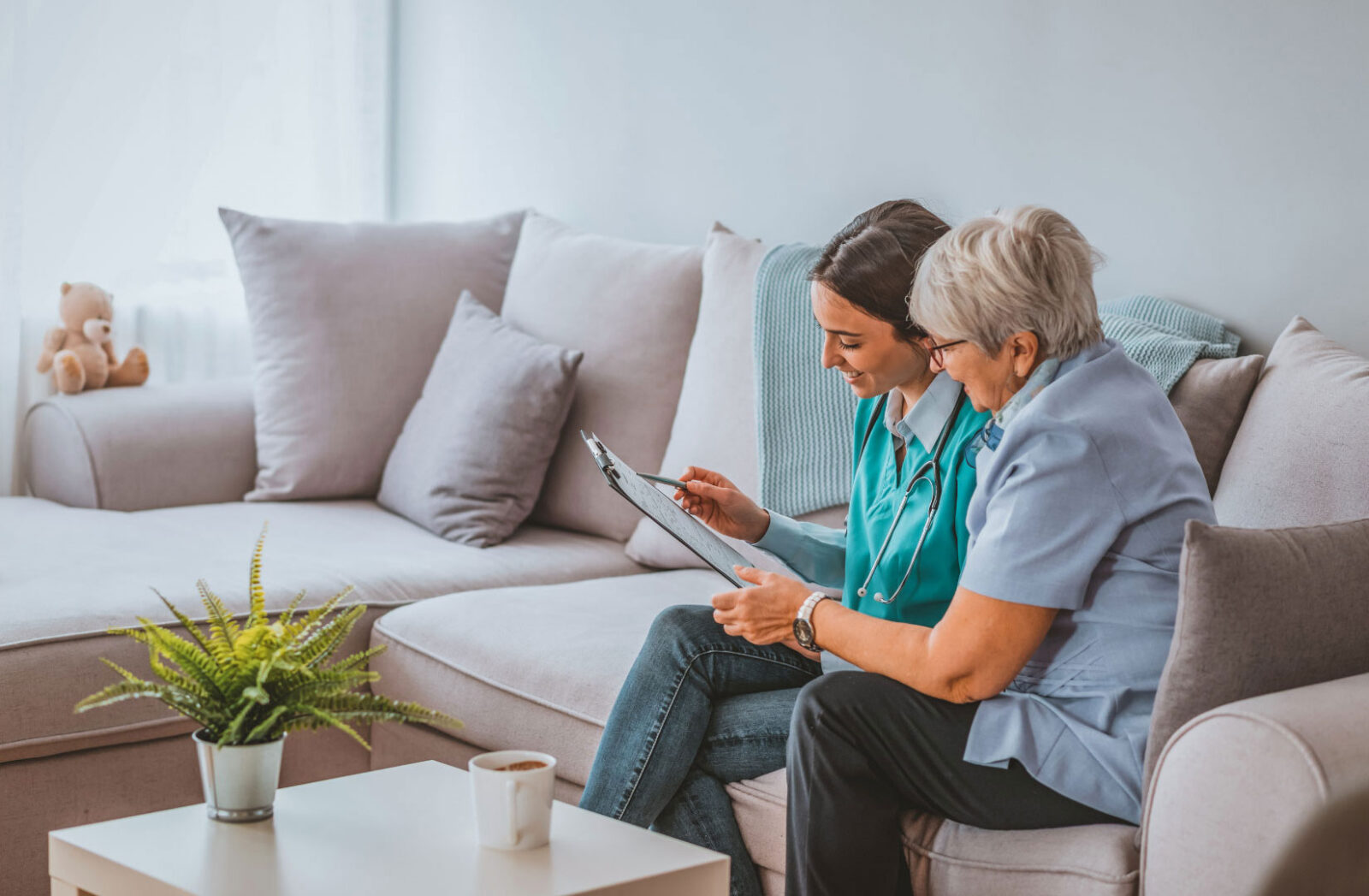 caregiver assisting elderly woman on a couch.