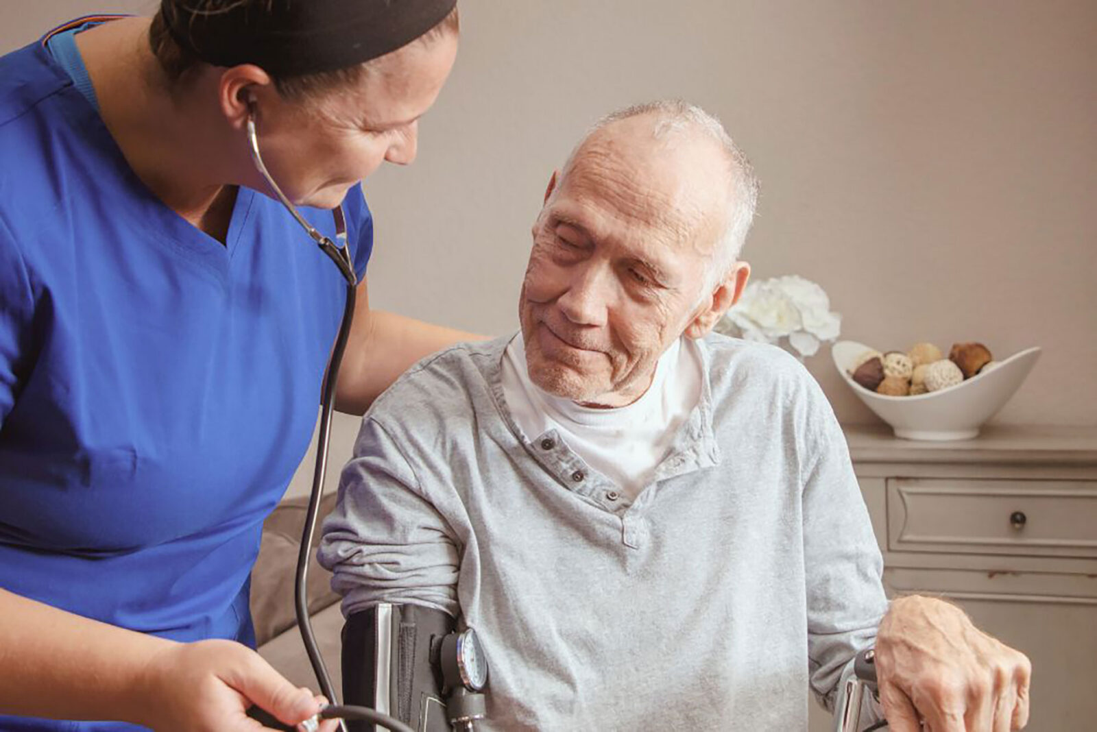 Nurse caring for elderly man in a warm setting.